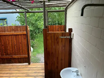 a bathroom with a wooden door and a sink at Swallows Cottages in Hermanus