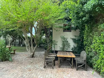 a wooden table and chairs in a garden at Swallows Cottages in Hermanus