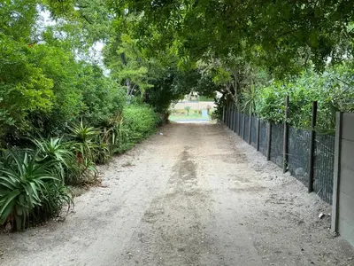 a dirt road with trees and a fence at Swallows Cottages in Hermanus