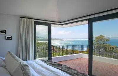 a bedroom with a bed and a view of the ocean at Hermanus Seafront Villa - Sophie's Rock in Hermanus