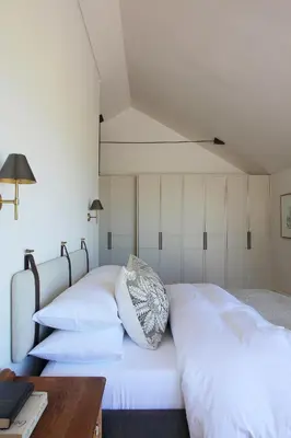 two beds in a room with white walls and a table at Hermanus Seafront Villa - Sophie's Rock in Hermanus