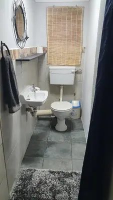 a bathroom with a toilet and a sink at Shalom Batchelor in Strand