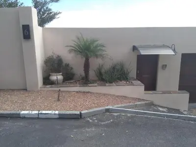 a house with a palm tree in front of it at View Panoramica Self-Catering Apartment in Gordonʼs Bay