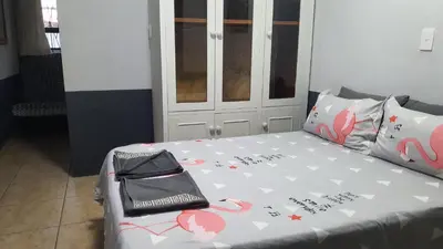 a bedroom with a bed with a gray comforter and aicter at Shalom Batchelor in Strand