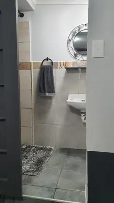 a bathroom with a sink and a mirror at Shalom Batchelor in Strand