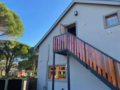 a white house with a staircase on the side at The Studio - a lovely 1 bed loft apartment in Somerset West