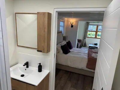 a bathroom with a sink and a bed and a mirror at The Cottage - a tranquil hideaway in Somerset West