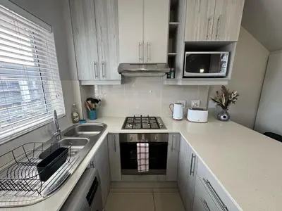 a kitchen with white cabinets and a sink and a microwave at Stylish Loft apartment in the heart of Durbanville in Durbanville