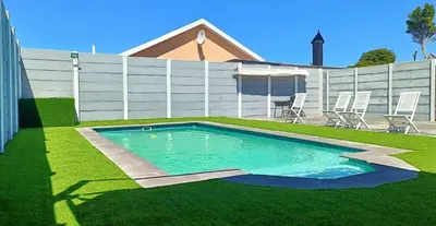 a swimming pool in a yard with chairs and a fence at Frangipani House in Goodwood