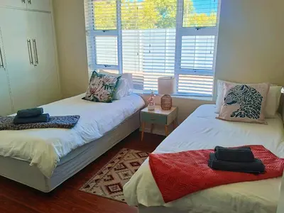 two twin beds in a room with windows at Frangipani House in Goodwood