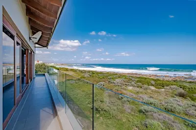 a balcony with a view of the beach at Lawaaiwaters in Hermanus
