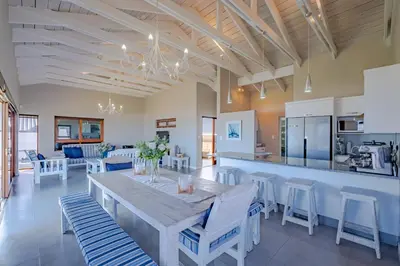 a dining room and kitchen with a table and chairs at Lawaaiwaters in Hermanus