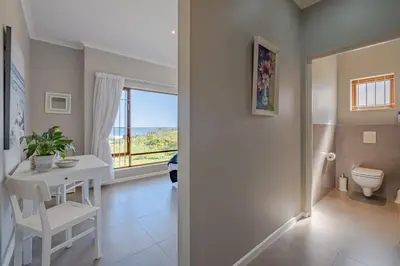 a bathroom with a table and a toilet and a window at Lawaaiwaters in Hermanus