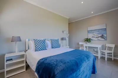 a bedroom with a large bed with a blue blanket at Lawaaiwaters in Hermanus