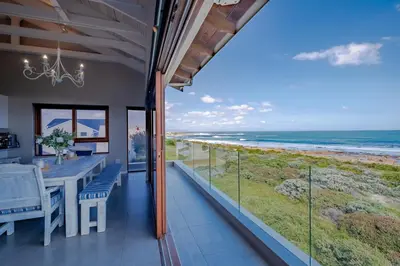 a dining room with a view of the ocean at Lawaaiwaters in Hermanus