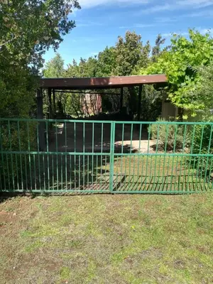 a fence in front of a park with a pavilion at Charming Rose Cottage in Greyton