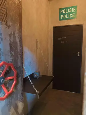 a policealling room with a black door and a red pair of handcuffs at Tether and Tease, The Fortress in Cape Town