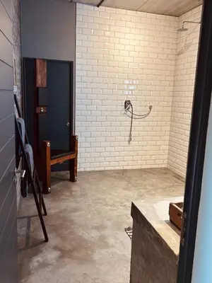 a shower in a room with a white brick wall at Tether and Tease, The Fortress in Cape Town