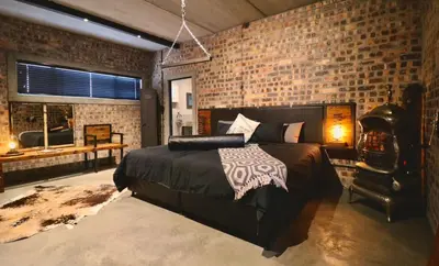 a bedroom with a bed and a brick wall at Tether and Tease, The Fortress in Cape Town