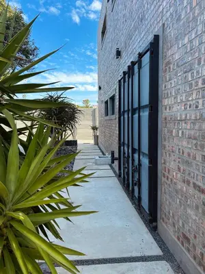 a brick building with a black door next to a sidewalk at Tether and Tease, The Fortress in Cape Town