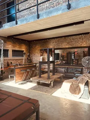 a room with wooden tables and a brick wall at Tether and Tease, The Fortress in Cape Town
