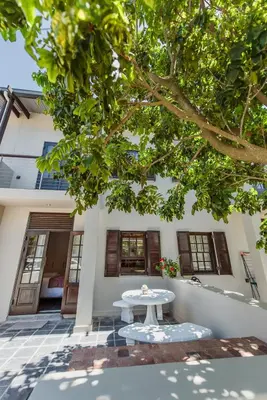 a white table under a tree in front of a house at Studio in Central Stellenbosch in Stellenbosch