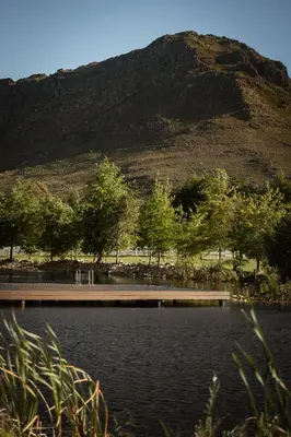 a bridge over a lake with a mountain in the background at Oakvale Estate in Franschhoek