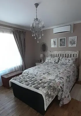 a bedroom with a large bed and a chandelier at De Kleine Herberg in Durbanville