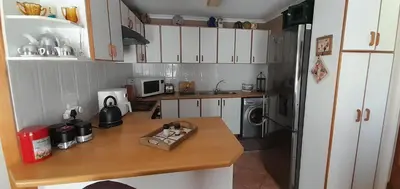 a kitchen with white cabinets and a wooden counter top at De Kleine Herberg in Durbanville