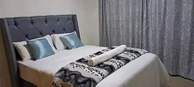 a bed with white sheets and blue pillows at Twinex Accommodation Parow in De Grendel