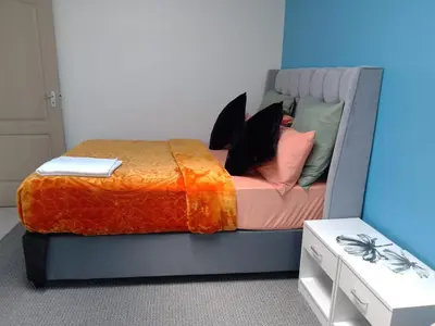 a bed with an orange blanket and pillows on it at Twinex Accommodation Bellville in Stikland