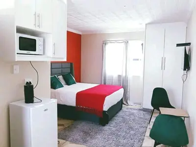 a bedroom with a bed and a tv on top of it at Twinex Accommodation Bellville in Stikland