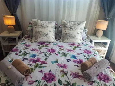 a bedroom with a bed with flowers and towels on it at Golfbeach Luxury self catering apartment in Cape Town