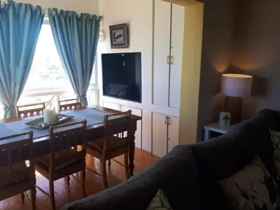 a living room with a dining table and a television at Golfbeach Luxury self catering apartment in Cape Town