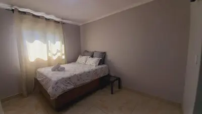 a small bedroom with a bed and a window at Zoe Apartment in Cape Town