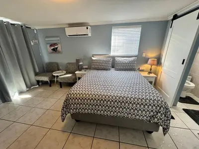 a bedroom with a bed and two chairs and a table at Pemba Guest Cape Town in Cape Town