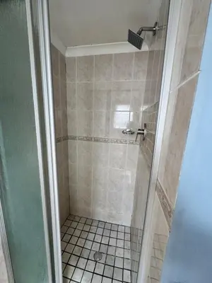 a bathroom with a shower with a tiled floor at Pemba Guest Cape Town in Cape Town