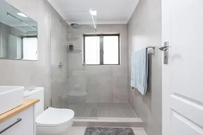a white bathroom with a toilet and a shower at Serenity at Cape Bay in Helderberg