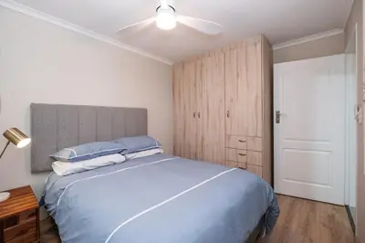 a bedroom with a blue bed and a ceiling fan at Serenity at Cape Bay in Helderberg