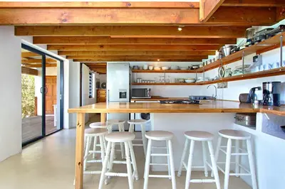a kitchen with a bar with stools in it at 82 Suikerbossie in Gordonʼs Bay