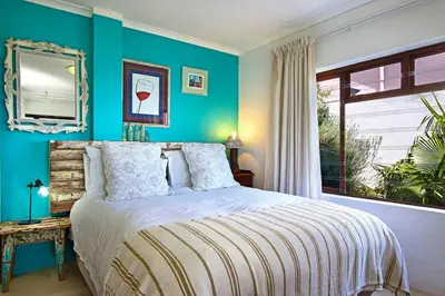 a bedroom with a bed with blue walls and a window at 82 Suikerbossie in Gordonʼs Bay