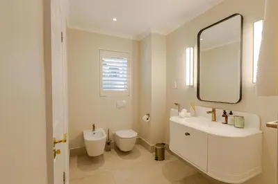 a bathroom with a sink and a toilet and a mirror at The Helderview Luxury Suites in Somerset West