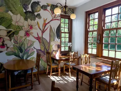 a dining room with tables and chairs and a floral wall at Vendome Wine Estate in Paarl