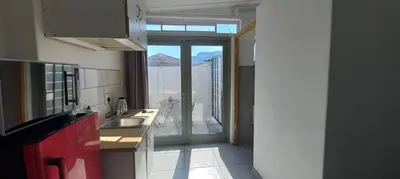 a kitchen with a sink and a view of a balcony at Kenwyn Micro Apartments in Cape Town