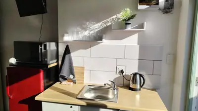 a small kitchen with a sink and a refrigerator at Kenwyn Micro Apartments in Cape Town
