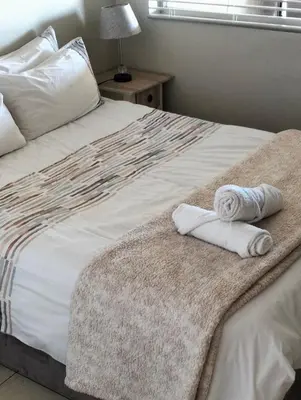 a bedroom with a bed with towels on it at Hermanus Beach Club 223 in Hermanus
