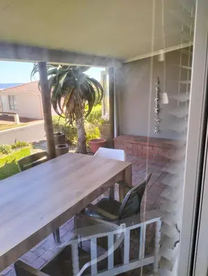 a table and chairs on a patio with a palm tree at Hermanus Beach Club 223 in Hermanus