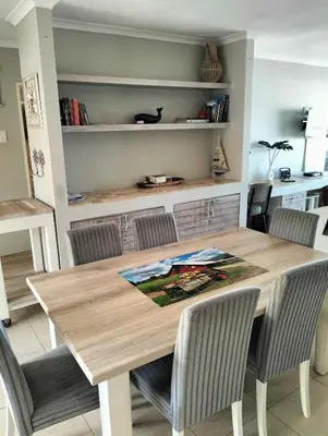 a dining room with a wooden table and chairs at Hermanus Beach Club 223 in Hermanus
