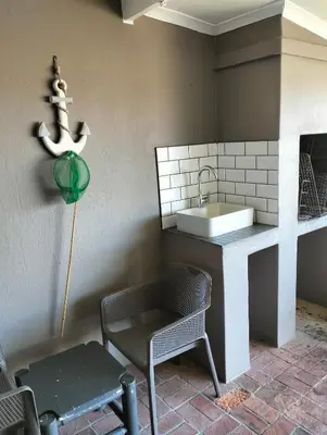 a kitchen with a sink and a chair and a table at Hermanus Beach Club 223 in Hermanus