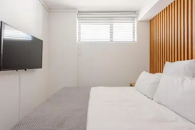 a bedroom with a white bed with a flat screen tv at Lifestyle Accommodation in Cape Town